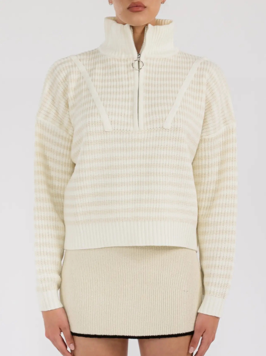 Person wearing a cream-colored ribbed sweater and skirt set on a white background