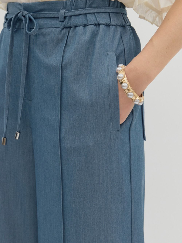 Blue pants with a drawstring waist on a plain background