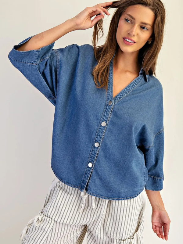 Woman wearing a blue denim shirt with a plain background
