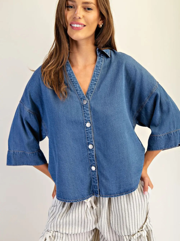Woman wearing a blue denim shirt with a plain background