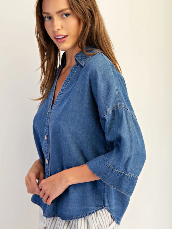 Woman wearing a blue denim shirt against a plain background