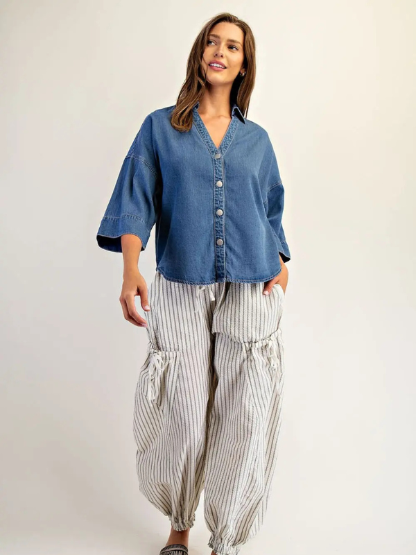 Woman wearing a blue shirt and striped pants on a plain background