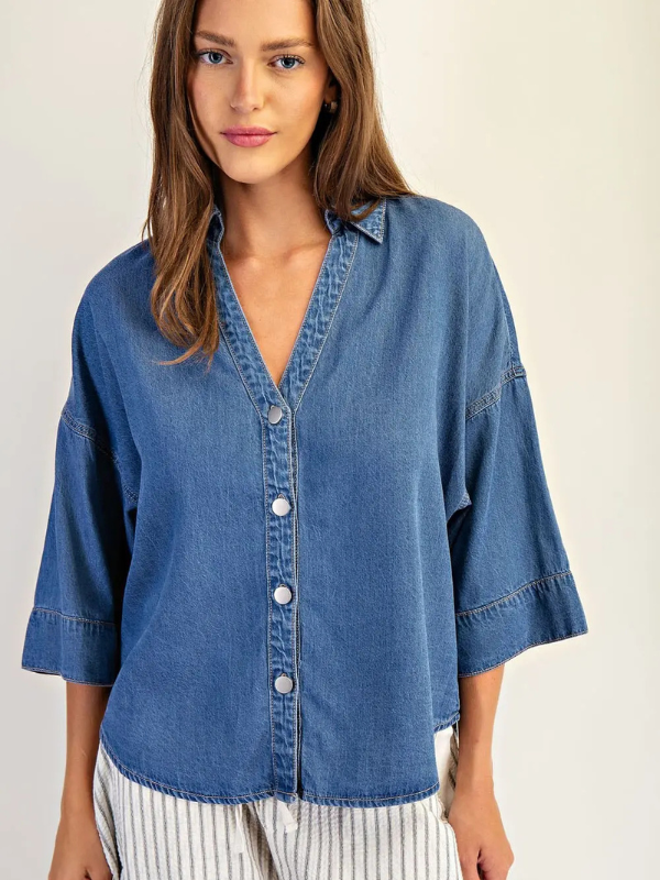 Woman wearing a blue denim shirt on a plain background