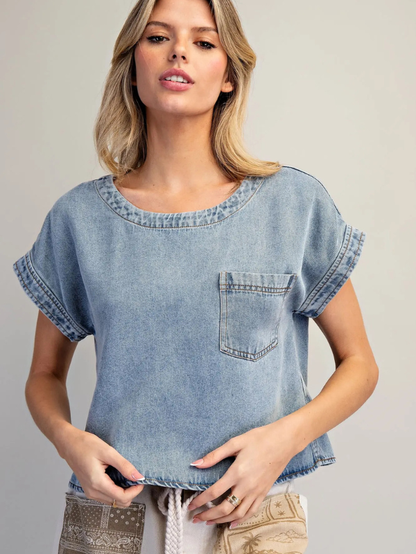 Woman wearing a denim top with a pocket on a plain background