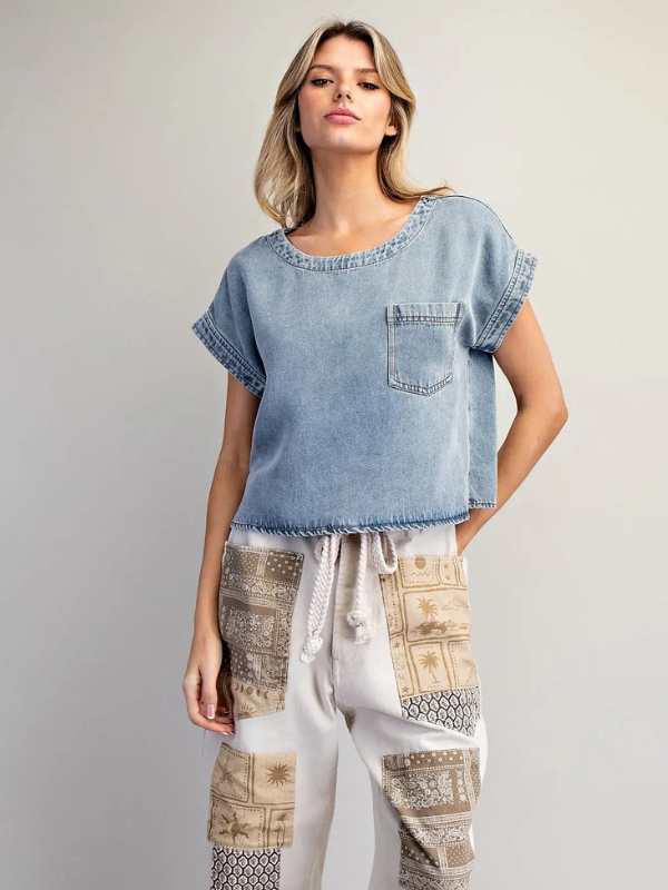 Woman wearing a denim top and patterned pants on a plain background