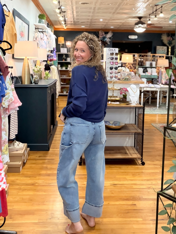 Woman in a store wearing a blue sweatshirt and light blue jeans, facing away from the camera.