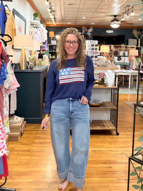 Woman wearing an American flag sweater and jeans in a store