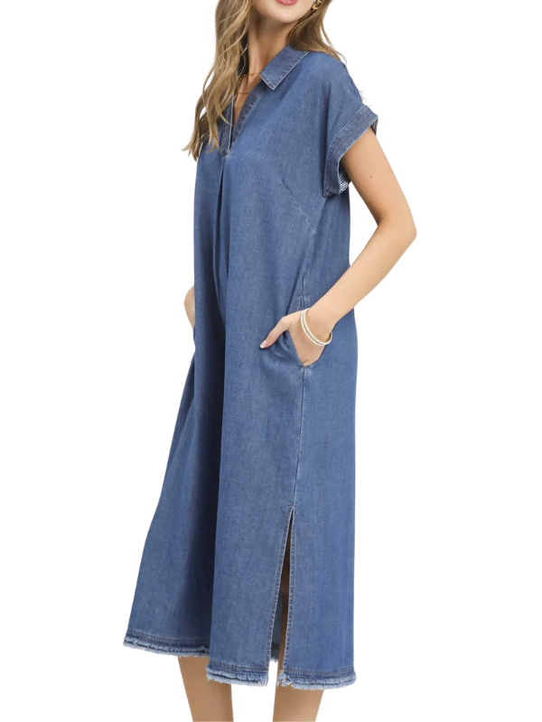 A woman wearing a blue denim midi dress with short sleeves, a collar, and side pockets, shown against a plain white background.