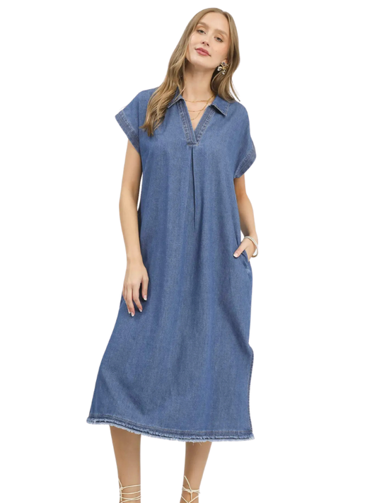 A woman modeling a short-sleeve blue denim midi dress with a buttoned collar and side pockets, set against a plain white background.