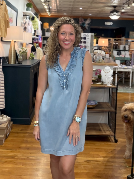 Woman wearing a light blue dress in a store setting with a dog in the background