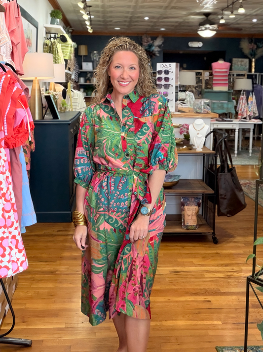 Woman in a colorful dress standing in a store with various items on display.