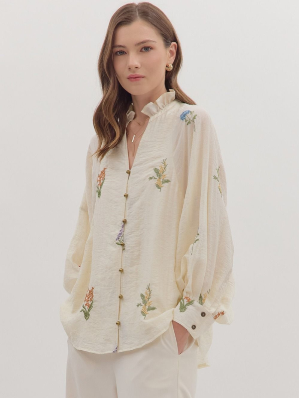 Woman wearing a cream-colored embroidered blouse against a white background