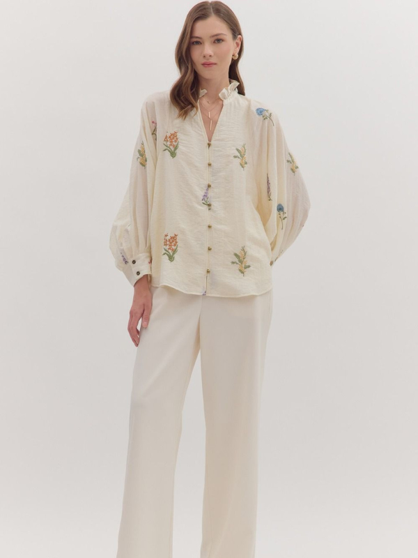 Woman wearing a beige embroidered blouse and pants on a white background
