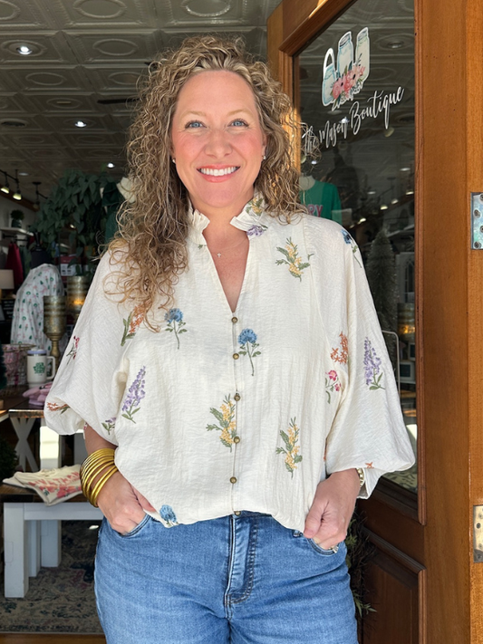 Woman wearing a floral blouse and jeans standing in a store.