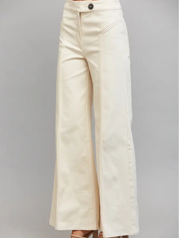 Cream wide-leg pants with diagonal seam detailing down the front of the legs, shown on a model from the waist down against a solid gray background.