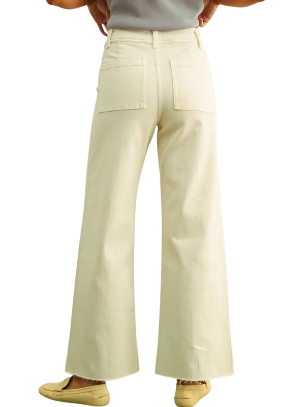 A person shown from the back wearing off-white wide-leg pants with two large back patch pockets, paired with a light gray top and tan slip-on shoes, against a plain white background.