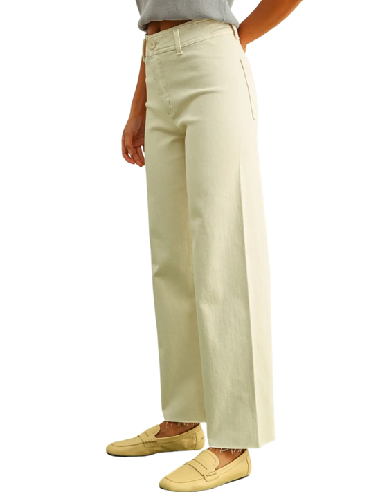 A person wearing light cream wide-leg cropped pants with a gray top and beige loafers, shown from the waist down on a white background.