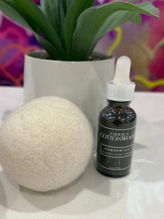 Bottle of 'House of Cottonwood' product with a spherical object and plant in the background