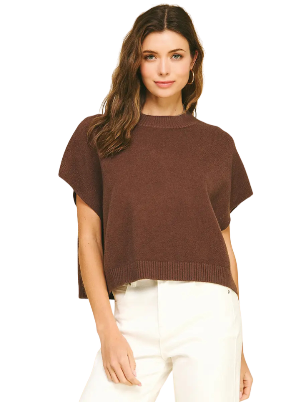 A woman modeling a brown short-sleeve knit sweater with a crew neck and ribbed hem, paired with white pants, against a plain white background.