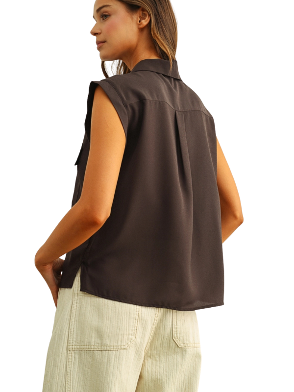 A woman shown from the back wearing a sleeveless dark brown collared shirt and light beige pants, photographed against a plain white background.