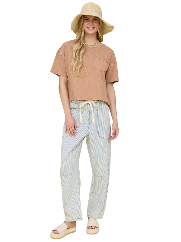 Woman wearing a brown top and light-colored pants with a beige hat on a white background