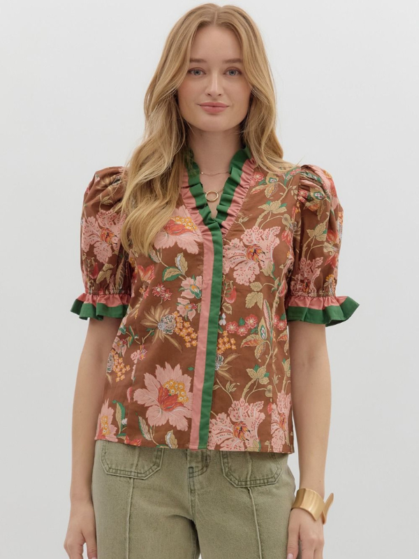 Woman wearing a floral blouse with puff sleeves on a plain background