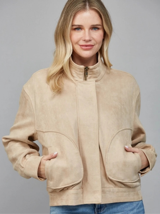 Woman wearing a beige jacket against a gray background