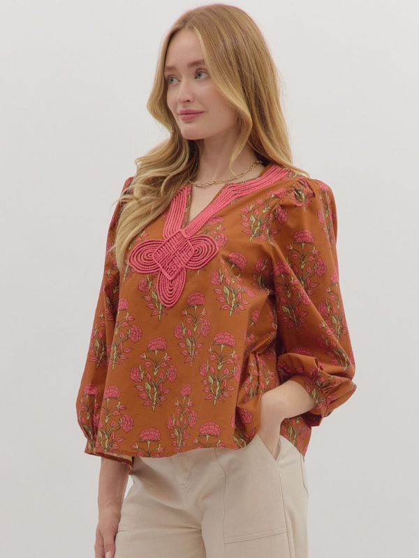 Woman wearing a patterned blouse with a butterfly design on a plain background
