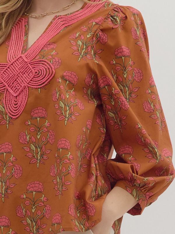 Brown dress with pink floral pattern and embroidery on a plain background