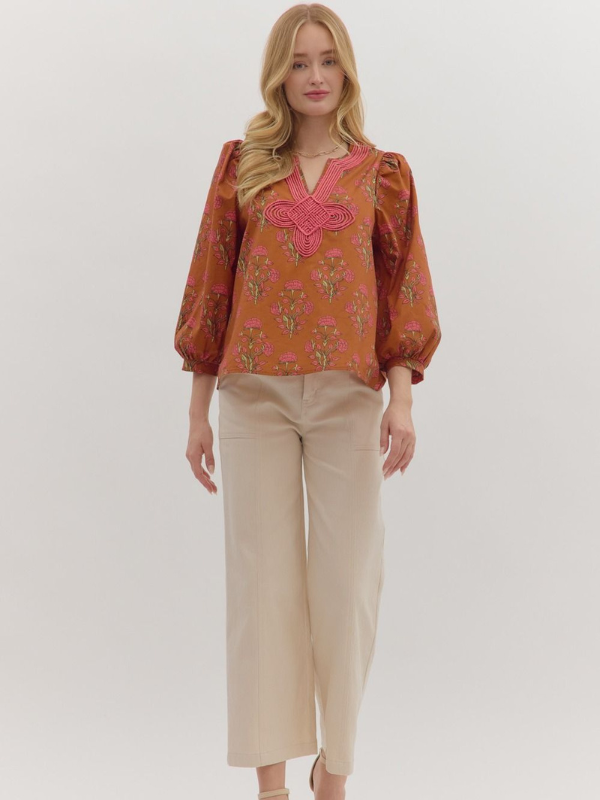 Woman wearing a patterned blouse and beige pants on a white background