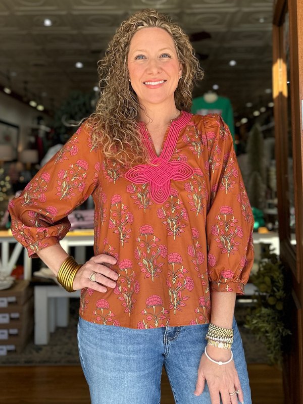 Woman wearing a patterned blouse with a blurred indoor background