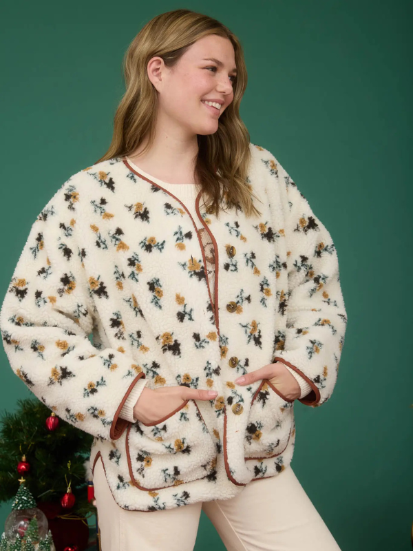 Woman wearing a floral patterned cardigan against a green background