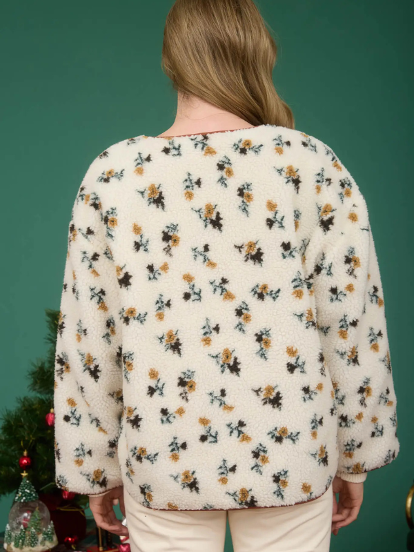 Person wearing a floral-patterned cardigan against a green background