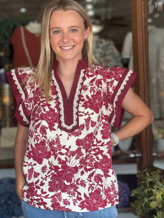 Woman wearing a floral blouse with maroon and white pattern in a store setting