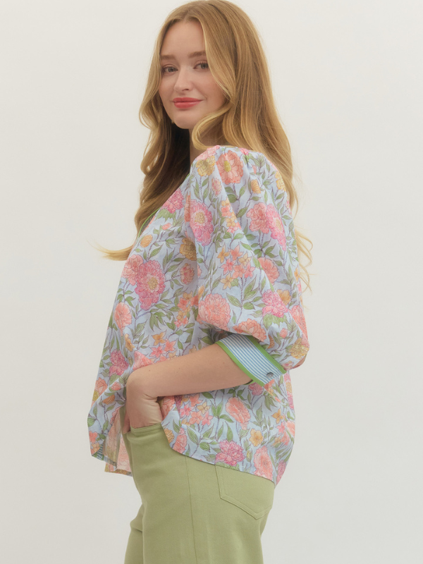 Woman wearing a floral kimono-style top with a plain background