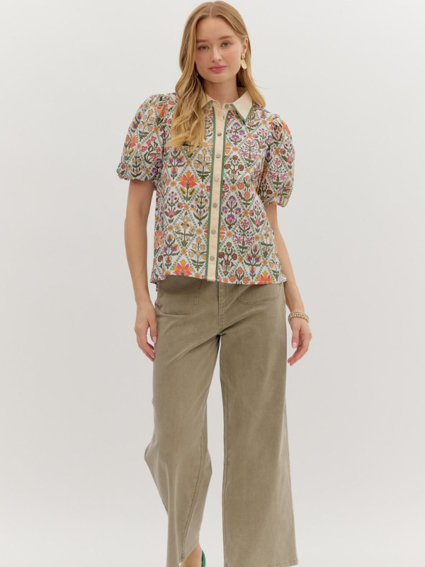 Woman wearing a patterned blouse and beige pants on a white background