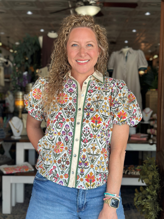Woman wearing a colorful floral blouse in a store setting