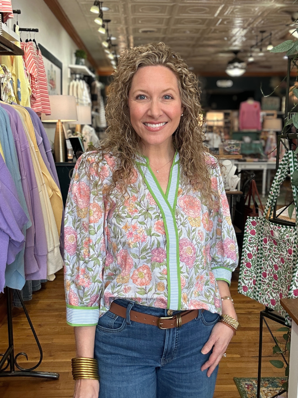 Woman wearing a floral blouse and jeans in a clothing store