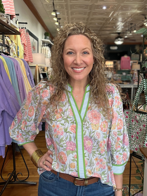 Woman wearing a floral blouse with a green zipper in a store setting