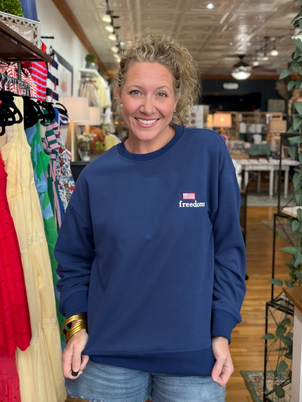 Woman wearing a blue sweatshirt with 'freedom' text in a store setting