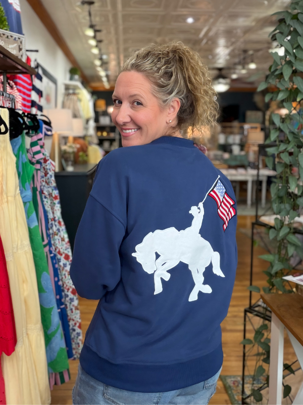 Woman wearing a navy sweatshirt with a white graphic design in a store setting