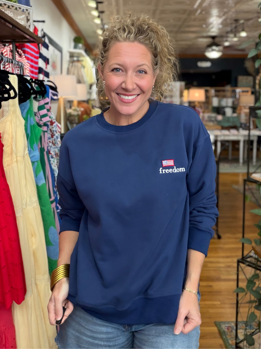 Woman wearing a blue sweatshirt with 'freedom' logo in a store setting