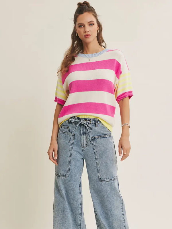 Woman wearing a colorful striped sweater and blue jeans on a plain background