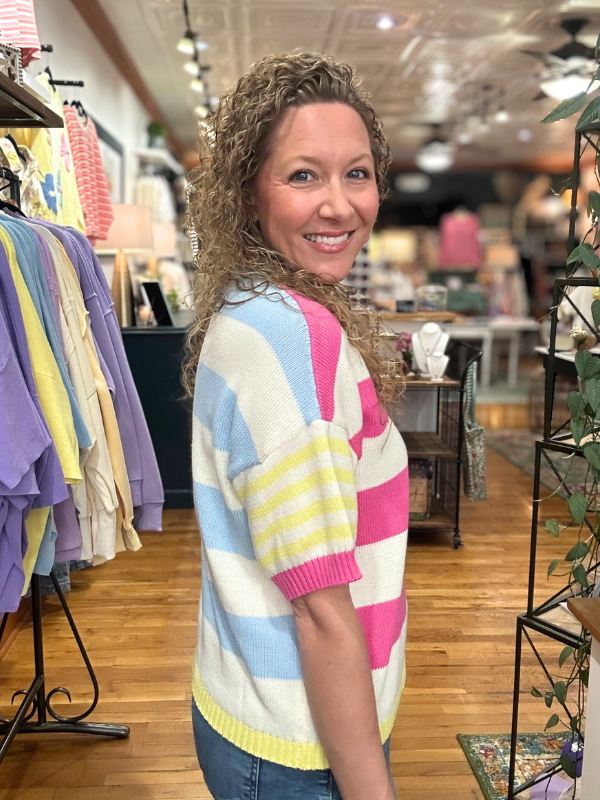 Woman wearing a colorful striped sweater in a store setting