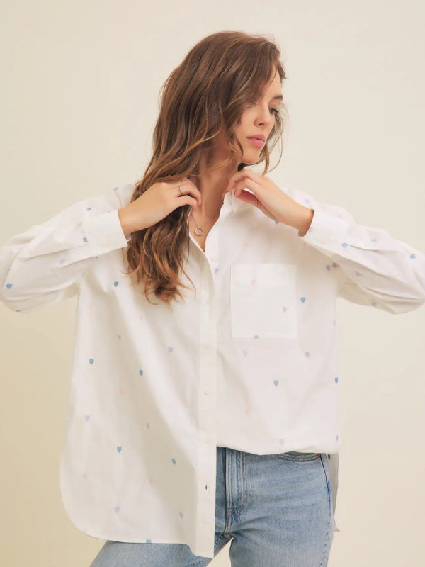 Woman wearing a white blouse with small patterns and blue jeans on a plain background