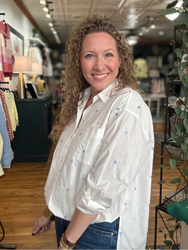 Woman in a white blouse with colorful patterns standing in a store.