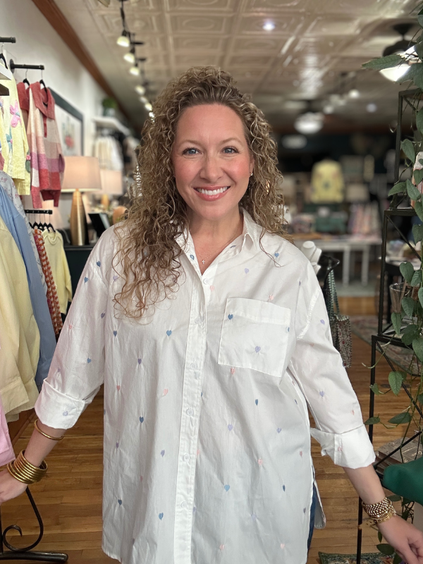 Woman wearing a white blouse with colorful patterns in a store setting