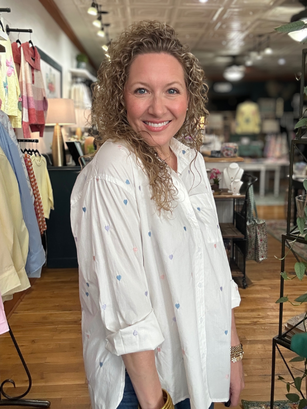 Woman in a white blouse with colorful dots standing in a store.