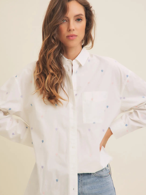 woman standing with white shirt with embroidered hearts on it 