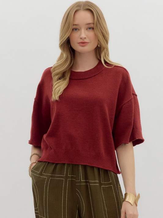 Woman wearing a red sweater and green pants on a plain background